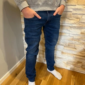 Replay Anbass jeans blå denim - Snygga Replay Anbass jeans i mörkblå denim med klassisk femficksdesign. Jeansen har smal passform, raka ben och tydliga sömmar. Perfekta för dig som gillar en stilren look med lite stretch för extra komfort. W29/L32