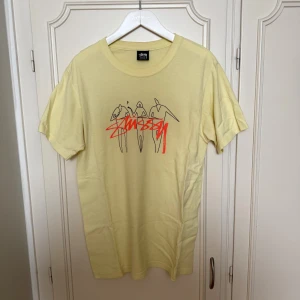 Helt ny Gul Stüssy t-shirt  - Fräsch gul t-shirt från Stüssy i storlek S, med coolt grafiskt tryck på bröstet och Stüssy-logga i rött
