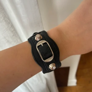 Balenciaga svart läderarmband - Supercoolt city armband från balenciaga som tyvärr inte kommer till användning. Lite slitning av silverplateringen på nitarna och även lite av sömmarna på bandet men inget man tänker på när man har det på sig, generellt mycket bra skick. 