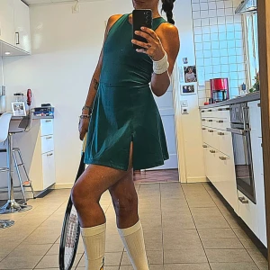 Grön tennisklänning  - Supersnygg grön tennisklänning med sportig känsla och slits framtill samt inbyggda shorts :) Ärmlös modell med tight passform upptill och utställd kjol. Perfekt för dig som gillar en aktiv och trendig look. Storlek small passar perfekt. Använd 1 gång