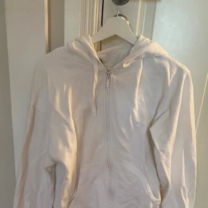 Vit hoodie  - Säljer en stilren vit hoodie från Cubus i ekologisk bomull. Tröjan har dragkedja framtill, huva med snörning och två fickor. Perfekt för en chill look och passar året runt. Enkel att matcha med jeans eller mjukisbyxor.