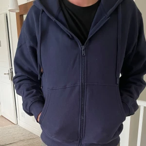 Mörkblå hoodie med dragkedja - Säljer en nästintill helt ny mörkblå hoodie från vailent med dragkedja framtill, huva med snörning och två stora fickor. Den har en lite croped look och är smått oversized. Tröjan är i storlek S men passar M.                 Priset som diskuteras  