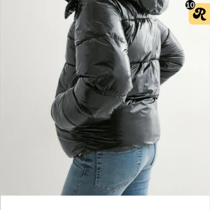 Svart jacka från nelly - Säljer en svart, glansig pufferjacka med huva och dragkedja framtill. Köpt på Nelly för 800kr och säljer den för 550. öppen för byten, sänker inte priset mer än 500