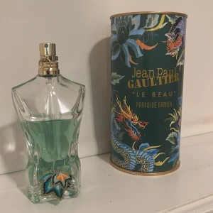 Jean Paul Gaultier Le Beau paradise garden  - Snygg och unik parfym med coolt drakmotiv på förpackningen. Flaskan har en grönblå färg och en stilren design. Perfekt för dig som vill sticka ut och ha något annorlunda i din samling. Modell: Le Beau Paradise Garden.