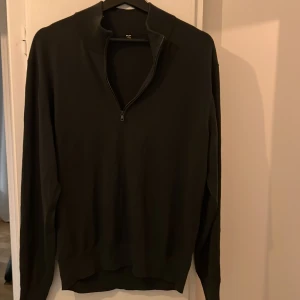 Mörk grön half zip tröja från Uniqlo - Mörk grön långärmad tröja från Uniqlo med half zip-dragkedja i halsen. Tröjan är i en stilren och enkel design, perfekt för lager-på-lager. Materialet är stickat och känns mjukt mot huden. Passformen är normal och kragen kan bäras både uppvikt och nedvikt.