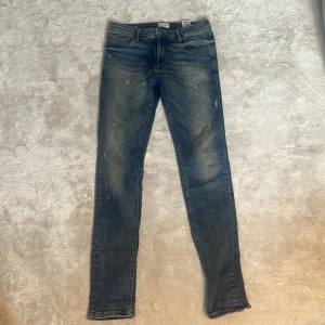 Blå skinny jeans Jack & Jones 30/34 - Säljer ett par blå skinny jeans från Jack & Jones i storlek 30/34. Jeansen har slitna detaljer och klassisk femficksdesign. De är tillverkade i stretchig denim för en bekväm passform och har snyggt tvättad look. Passar L33 