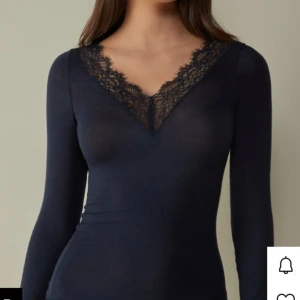 Marin blå Intimissi tröja - Säljer en svart långärmad topp med v-ringning och fina spetsdetaljer vid halsringning och ärmslut. Sitter tight och har en elegant look som lyfter outfiten. Perfekt att styla med jeans eller kjol. Inte använt mycket för gillar it så mycket