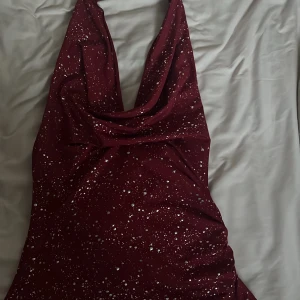 Vinröd glittrig topp - Säljer en vinröd topp med glittriga detaljer och djup urringning.🤎