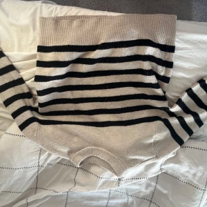Randig stickad tröja från H&M - Beige och svart randig stickad tröja från H&M i storlek S. Tröjan har rund halsringning och långa ärmar. Perfekt för dig som gillar en klassisk och chill stil med lite oversized känsla.