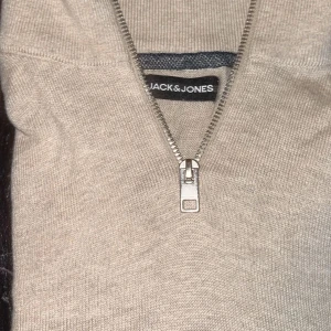 Beige stickad half zip från Jack & Jones - Snygg beige stickad tröja från Jack & Jones med half zip-dragkedja framtill. Perfekt för lager-på-lager och enkel att matcha med jeans eller chinos. Mjuk och skön känsla, passar dig som gillar stilrena plagg med en clean look.