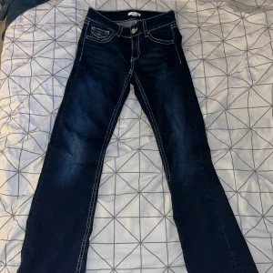 Mörkblå bootcut jeans Gina Tricot  - Snygga mörkblå jeans från Gina Tricot i storlek 164. Modellen har bootcut-ben, markerade kontrastsömmar och klassiska fickor både fram och bak. Jeansen är tillverkade i jeansmaterial och har en midja med knapp och dragkedja. 