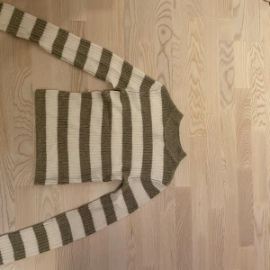 Randig ribbstickad tröja från H&M Divided - Superfin ribbstickad tröja från H&M Divided i beige och olivgrönt. Tröjan har breda horisontella ränder, rund hals och långa ärmar. Perfekt för lager-på-lager och chill vibes.