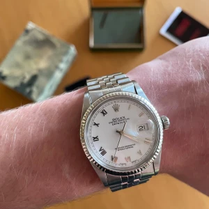 Rolex Datejust 36 mm  - Säljer nu min Rolex Datejust 36 mm i fint skick utförd i stål med vitguldsring. Klockan servades den 25 Juli 2025 och går inom 2 sekunder per dygn vilket är ett väldigt bra resultat. Orginaltillbehör och service resultat medföljer självklart vid köp.   Info:   Refnr: 16014  Årsmodell: 1985  Skick: Bra  Urtavla: Roman  Bezeln: 18 k vit guld  Boett: Stål Armband: Jubilee, stål Lås: Viklås,stål  Pris = 58 999 kr (diskuterbart)   Kom pm vid fler frågor eller bilder!   MVH Anton Fölstad
