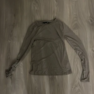Beige långärmad topp från 157 - Säljer en beige långärmad topp från 157 i storlek XS. Modellen är tight och har en enkel, stilren design med rund halsringning. Perfekt att styla med jeans eller kjol för en clean look.