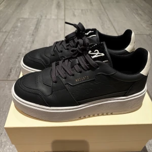 Navy  sneakers från Axel Arigato - Snygga navy  sneakers från Axel Arigato med vit sula och vit detalj på hälen. Skorna har snörning, rund tå och är tillverkade i skinn, låda och dust bag medföljer Perfekta för dig som gillar stilrena och trendiga sneakers.