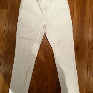 Vita linnebyxor från Riley - Snygga vita linnebyxor från Riley i regular fit. Byxorna har klassisk rak passform och är tillverkade i svalt och skönt linne, perfekta för varmare dagar. Stilrena och enkla att matcha med det mesta. Storlek 42