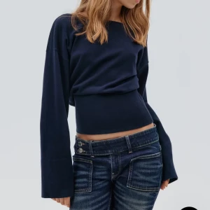 Mörkblå stickad tröja med v-ringad rygg - Mörkblå stickad tröja med breda ärmar och tajt midja. Tröjan har en v-ringning i ryggen. Säljer för att den aldrig kommit till användning. 