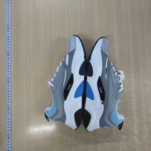 Dior sneakers i grått, vitt och blått - Säljer ett par feta Dior sneakers med chunky sula. Skorna har en mix av grått, vitt och blått med svarta detaljer och reflekterande partier. Ovandelen är i mesh och syntet med snörning och coola paneler. Perfekta för dig som vill sticka ut med en lyxig streetstyle.