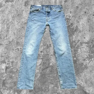 Levis 501 ljusblå jeans - Klassiska Levis 501 jeans i ljusblå denim med raka ben och femficksmodell. Byxorna har knappgylf och den ikoniska Levis-lappen bak i midjan. Perfekta för en avslappnad och tidlös stil. Pris kan diskuteras🤝
