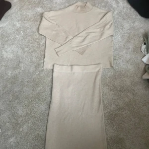 Beige set  - Säljer en beige, ribbstickad tröja och långkjol i set. Kjolen har en rak och enkel siluett med mjukt stickat material som känns supermysigt. Perfekt för dig som gillar en clean och stilren look. Kjolen är midjehög och passar till många olika outfits.