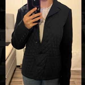 Svart quiltad jacka från Burberry Brit - svart quiltad jacka från Burberry Brit, knappar framtill och två stora fickor. Jackan har släta svarta ärmar. Priset kan diskuteras, jackan är nästintill ny, använd få gånger och ja den är stolek M men den är liten i storleken. 