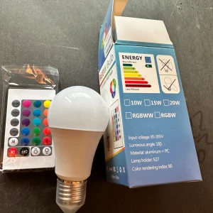 RGBW Bulb med fjärrkontroll lampa  - Smart RGBW LED-lampa med 24-knapps fjärrkontroll. Välj mellan 15 färger, RGB-flash och olika ljuslägen. Passar E27-sockel, 10/15/20W, bred ljusspridning (180°). Ny i förpackning, komplett med fjärrkontroll. Perfekt för stämningsbelysning.