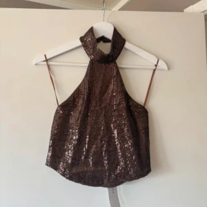 Brun paljett halterneck topp Gina Tricot - Oanvänd Snygg brun paljettopp från Gina Tricot med halterneck. Stl S. knäpps i nacken. Lapp kvar på 