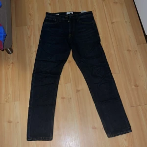 Mörkblå Relaxed/Chris jeans 29/32 - Mörkblå jeans från Jack & Jones i modellen Relaxed/Chris. Klassisk femficksdesign, raka ben och avslappnad passform. Jeansen har kontrastsömmar och är tillverkade i slitstarkt denimtyg. Perfekta för dig som gillar en lite lösare stil.