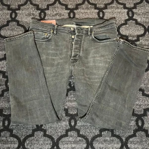 Grå jeans från Acne Studios Blå Konst - Säljer ett par grå jeans från Acne Studios Blå Konst, modell med klassisk femficksdesign och knappgylf. Jeansen har raka ben och en snygg tvättad finish. Perfekta för dig som gillar stilrena och trendiga byxor.