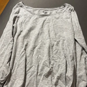 Ljusgrå långärmad tröja från 157 - En basic ljusgrå långärmad tröja från 157 med rund halsringning. Tillverkad i mjuk bomullsmix, perfekt för lager-på-lager eller chill dagar. Enkel och stilren design som funkar till det mesta.