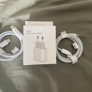 USB-C 20W Power Adapter med kablar - Apple USB-C 20W Power Adapter med två USB-C till Lightning-kablar. Perfekt för snabb laddning av iPhone eller iPad. Alla delar ser nya och oanvända ut, inga synliga skador eller slitage. Komplett i originalförpackning. OBS!! Du får en adapter och en kabel att välja på finns flera om man vill köpa åt hela familjen 