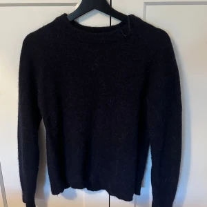 Mörkblå stickad tröja Zara  - En enkel och stilren mörkblå stickad tröja med rund halsringning. Tröjan har lång ärm och är gjord i ett mjukt, fluffigt material som känns riktigt mysigt. Perfekt för kyliga dagar när du vill ha något bekvämt och snyggt.