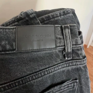 Svarta raka jeans från Gina Tricot - Snygga svarta jeans från Gina Tricot i premium denim. Jeansen har hög midja och raka ben med klassisk femficksdesign. Materialet är robust denim med en tvättad svart färg som ger en cool vibe. Perfekta för dig som gillar en tidlös och trendig look.