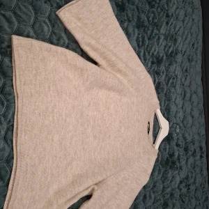 Beige stickad tröja från Gina Tricot - Mysig beige stickad tröja från Gina Tricot i storlek M. Tröjan har en enkel och clean design med rund halsringning och långa ärmar. Perfekt för lager-på-lager och chill höst- och vinterdagar.