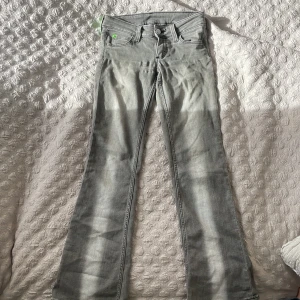 Grå bootcut jeans från Cheap Monday - Säljer ett par gråa bootcut jeans från Cheap Monday i storlek 28/30. Jeansen har klassisk femficksdesign, normal passform och är tillverkade i en mix av bomull, polyester och elastan. Snyggt slitna detaljer och en cool, ljusgrå tvätt.