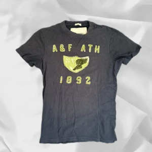 Abercrombie & Fitch - Abercrombie & Fitch t-shirt i storlek M extremt eftertraktad – enkel att matcha och skön att bära. Ett stilrent val, noggrant utvalt med omsorg av AM Clothing.  📩 Frågor? Hör gärna av dig! 📲 Följ oss här på Plick för fler uppdateringar. ♻️ Tack för att du handlar mer hållbart med AM Clothing!