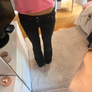Svarta bootcut jeans från Gina Tricot  - Svarta jeans från Gina Tricot i storlek 36. Modellen har bootcut-ben och klassisk femficksdesign. Jeansen är i stretchigt denimtyg som sitter snyggt och bekvämt. Perfekta för dig som gillar en tidlös och clean look.