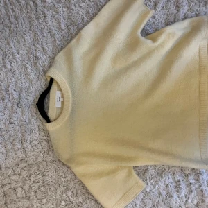 Ljusgul stickad tröja från Gina tricot  - Superfin ljusgul stickad tröja från gina tricot med korta ärmar och rund halsringning. Tröjan har en mjuk och fluffig känsla, perfekt för lager på lager eller som den är. Enkel och stilren design som passar till allt.