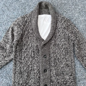 Grå stickad cardigan med knappar - Säljer en mysig grå stickad kofta med snyggt mönster och stora knappar. Koftan har en bred krage och skön passform. Perfekt för vintern!