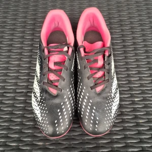 Adidas Predator fotbollsskor svart/rosa - Säljer ett par Adidas Predator fotbollsskor i svart med vita detaljer och rosa insida. Skorna har snörning och är designade med mönstrade vita ränder på sidorna. Perfekta för dig som vill sticka ut på planen med snygg stil och bra grepp.
