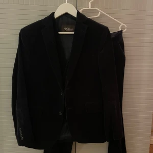 Svart manchesterkostym Oscar Jacobson - Säljer en svart manchesterkostym från Oscar Jacobson. Setet består av kavaj, byxor och väst i klassisk modell. Kavajen har knappar framtill och fickor, byxorna har raka ben och västen har knäppning framtill. Priset är ej hugget i sten kan gå ner i pris vid snabb affär!!