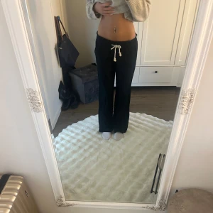 Svarta linnebyxor från Roxy med snörning - Svarta linnebyxor från Roxy med bred resår i midjan och vit snörning framtill. Byxorna har raka ben, två bakfickor och en avslappnad passform. Perfekta för en chill och stilren look.