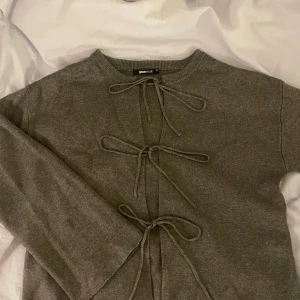 Grå kofta med knyt från Gina Tricot - Mysig grå kofta från Gina Tricot med tre snygga knyt framtill. Koftan är stickad och har långärmad modell, perfekt för lager-på-lager. Enkel och stilren design som passar till allt.