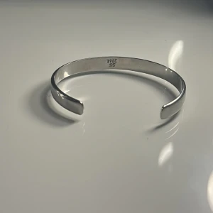 Stilrent silverfärgat armband i stål - Snyggt och minimalistiskt armband i blankt rostfritt stål med öppen design. Silverfärgad och enkel att matcha med andra smycken.