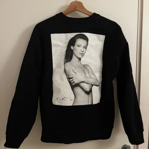 Svart sweatshirt Kate Moss Zara S - Cool svart sweatshirt från Zara med ikoniskt fototryck av Kate Moss på framsidan, fotograferad av Terry O’Neill. Tröjan har rund hals, lång ärm och tryckt text på bröstet. Perfekt statement-plagg för dig som gillar mode och foto.
