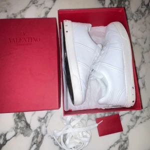 Valentino flycrews - Snygga vita sneakers från Valentino Garavani i skinn med klassisk låg siluett och coola nitar på hälen. Skick 9/10, storlek 40, sitter extremt bra, fraktar direkt, 1 nitt borta men inget mer, inga defekter, tveka inte på att höra av er!