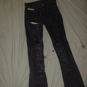 Svarta Diesel Safado jeans, W29 L32 - Säljer ett par svarta Diesel Safado jeans med slitna detaljer och snygga trasiga partier framtill. Klassisk femficksmodell med raka ben och diskreta logodetaljer. Jeansen är i denim och har en cool, mörk tvätt som passar till det mesta.