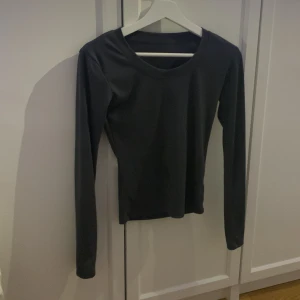 Svart långärmad topp med rund hals - En stilren svart långärmad topp med rundad halsringning. Modellen är figurnära och har en enkel, clean look utan detaljer eller mönster. Perfekt att matcha med jeans eller kjol för en chill och snygg vibe.