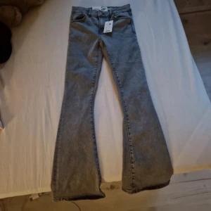 Gråa flare jeans från 157 Skippy - Snygga gråa jeans från 157 i modellen Skippy Flare. Jeansen har klassisk femficksdesign, utsvängda ben och normal passform. Perfekta för dig som gillar en retroinspirerad look med moderna vibbar. Tillverkade i mjukt jeanstyg för skön känsla hela dagen.
