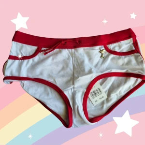 Snobbentrosor med röd kant storlek S - Supergulliga vita hipstertrosor med röda kanter och snörning i midjan. Framtill finns en liten Snoopy-charm och baktill ett tryck med Snoopy i rött. Mjukt material i 95% bomull och 5% elastan för skön passform. Perfekt för dig som gillar söta detaljer och tecknade motiv. Är aldrig använd, kommer från ett konkurslager. Se även mina andra auktioner. Bundlerabatt på 20% vid flerköp. 